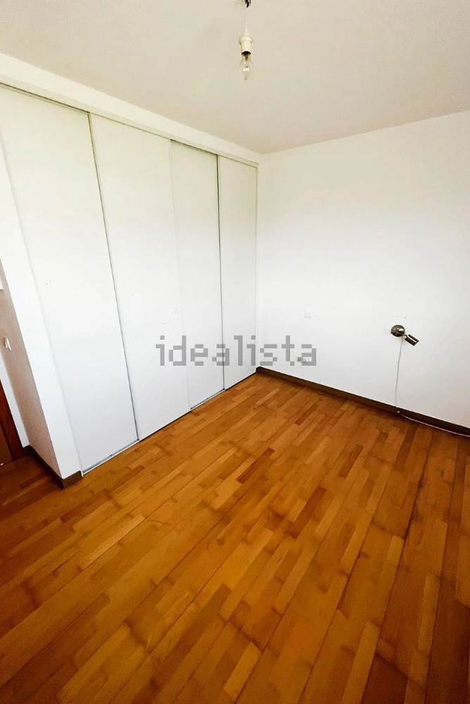 habitación con suelo laminado y armario empotrado blanco